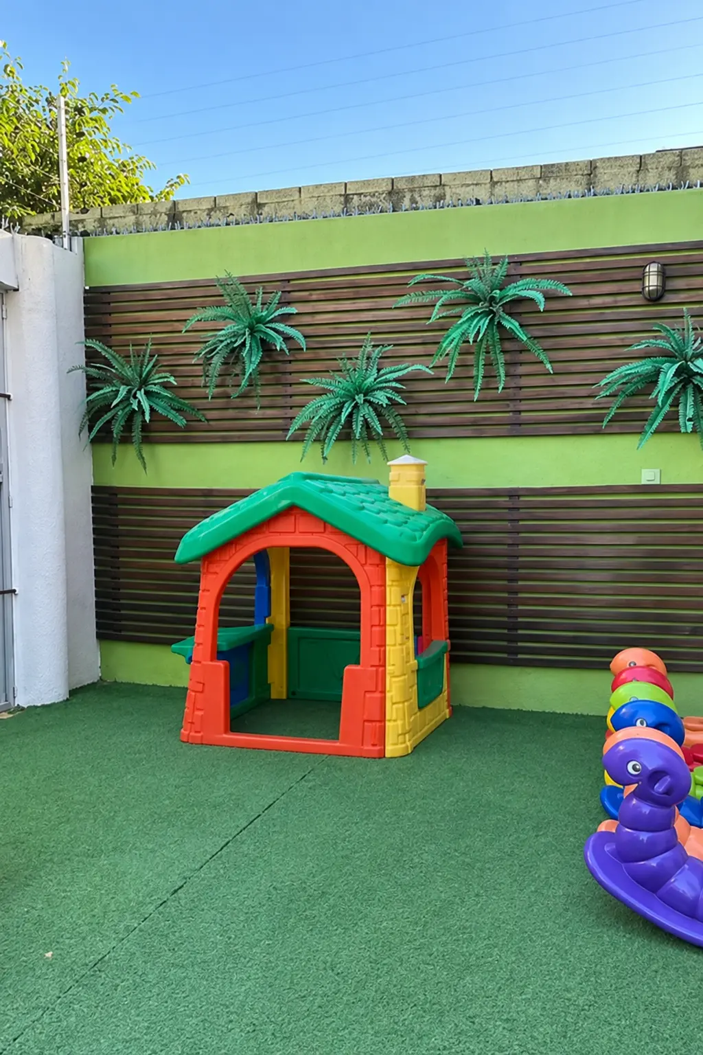 Área externa com gramado, casinha e brinquedos coloridos