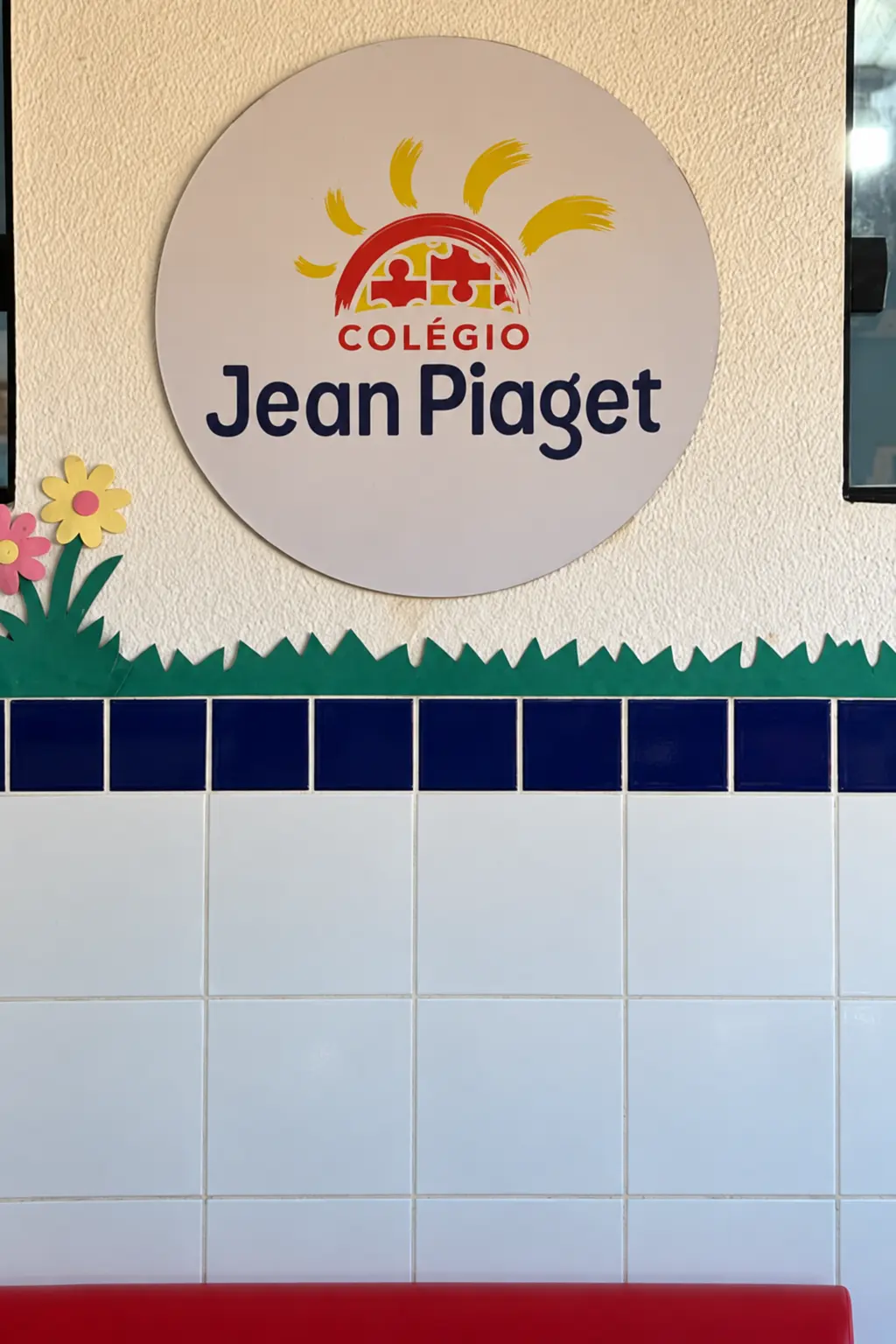 Recepção do Colégio Jean Piaget com a placa da logo na parede